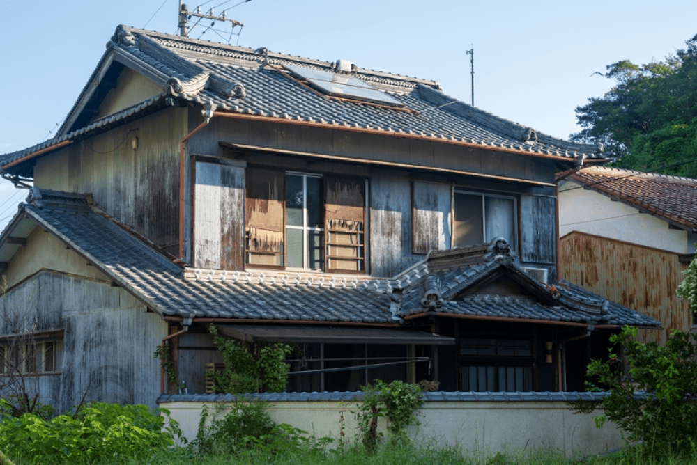 窓際に山積みになった書類や箱が置かれた室内。